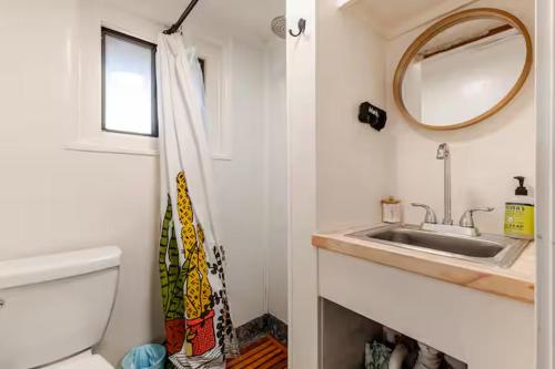 a bathroom with a sink and a toilet and a mirror at Brews, Bites, & Pines - Your downtown Flagstaff suite in Flagstaff