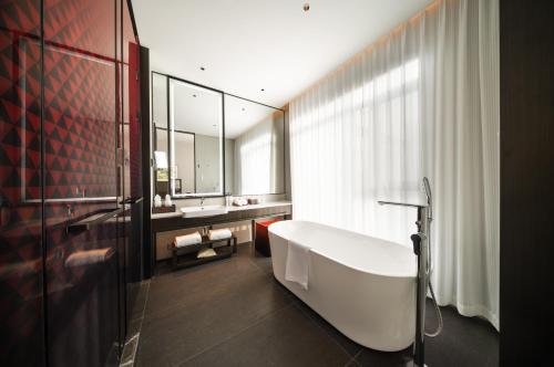 a bathroom with a bath tub and a mirror at Madison Hotel Jinan CBD in Jinan