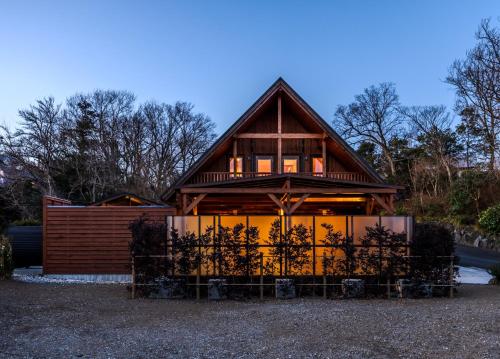 a house with a large window and a fence at P's Wood 伊豆高原 ー温泉大浴場 露天風呂 サウナ 屋根付BBQを満喫ー in Ito