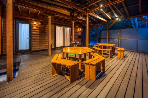 a room with wooden tables and benches on a deck at P's Wood 伊豆高原 ー温泉大浴場 露天風呂 サウナ 屋根付BBQを満喫ー in Ito