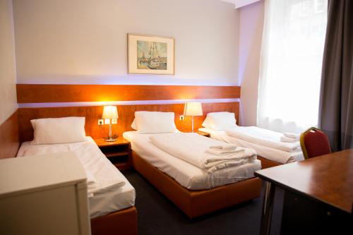Habitación de hotel con 2 camas y mesa en City Hotel - HEEFA OHG en Hamburgo