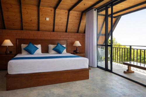 a bedroom with a large bed and a balcony at Forest Edge Resort in Kitulgala