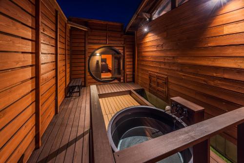 a bathroom with a tub in a wooden cabin at P's Wood 伊豆高原 ー温泉大浴場 露天風呂 サウナ 屋根付BBQを満喫ー in Ito