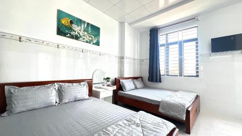 a bedroom with two beds and a window at Nhà Nghỉ Như Ý in Phan Rang–Tháp Chàm