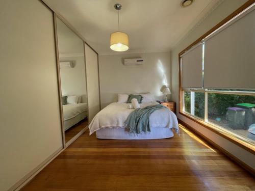 a bedroom with a bed and a large window at House on Heron in Mildura