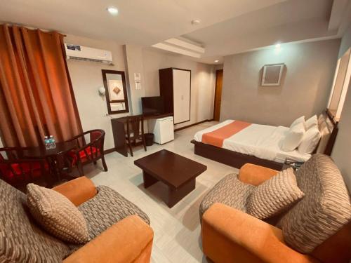 a hotel room with a bed and two chairs at Roxas Midtown Hotel in Roxas City