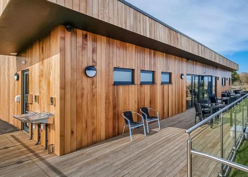 a wooden building with chairs on a deck at Woodlands Park Lodges At Haystax in Knitsley