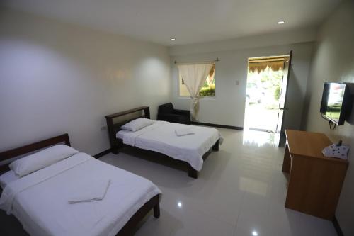 a hotel room with two beds and a television at Meg's Resort in Andoon