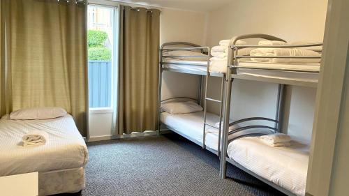 a room with three bunk beds and a window at Pelicans Perch - Scenic Coastal Retreat in Lake Tyers