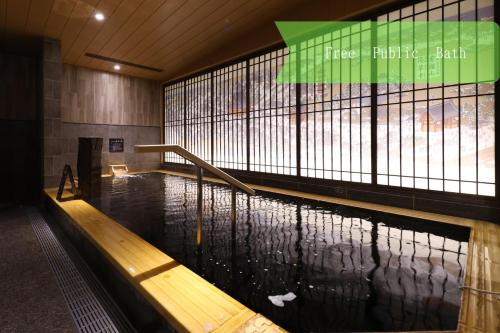 a pool of water with a wooden bench in a building at Onyado Nono Asakusa Annex - Natural Hot Spring in Tokyo