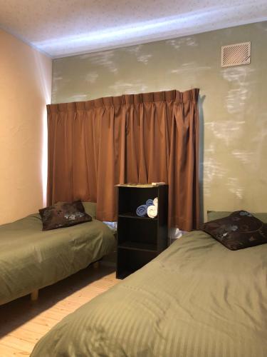a room with two beds and a window with curtains at Cozy Penguin House Bibai in Bibai