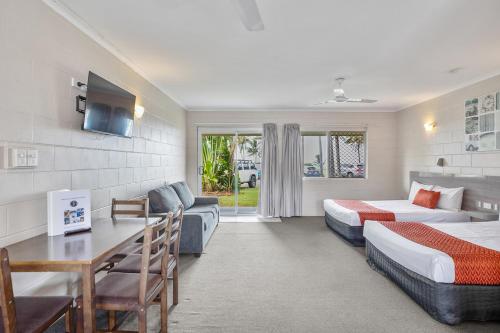 a hotel room with two beds and a desk at Sarina Beach Motel in Sarina