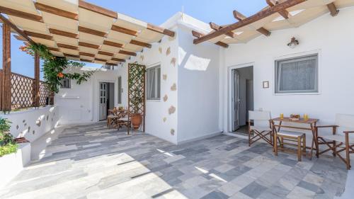 a patio with tables and chairs and a wooden pergola at Casa de Flores 1 in Plaka Milou