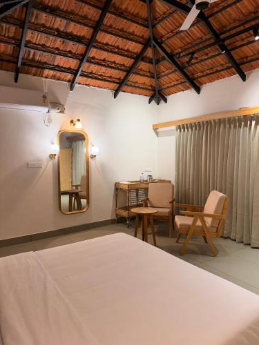 a bedroom with a bed and a desk and a mirror at Bhoomi by Ostello in Varkala