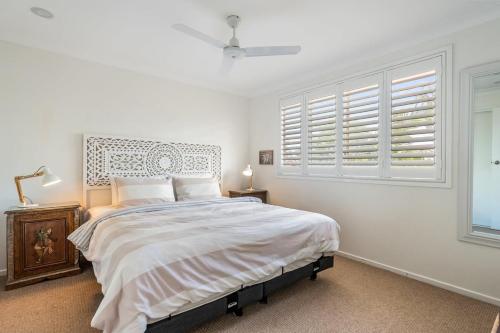 a white bedroom with a large bed and windows at Sea Haven in Lennox Head