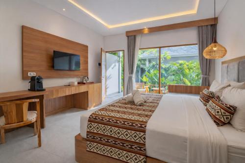 a hotel room with a bed and a television at Casa Wina Kuta by The Wina Resorts in Kuta