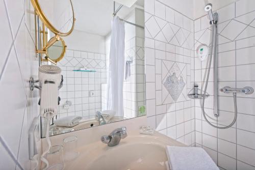 a white bathroom with a sink and a shower at Wyndham Garden Lahnstein Koblenz in Lahnstein