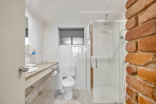 a white bathroom with a toilet and a shower at Sarina Beach Motel in Sarina