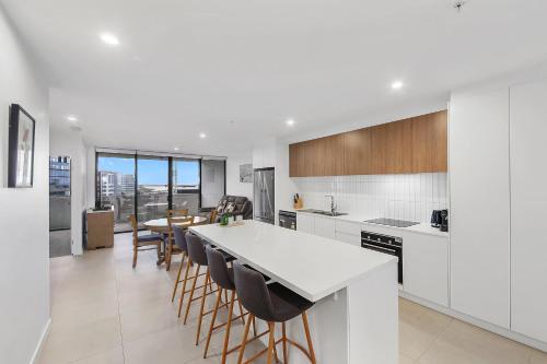 a kitchen with white counters and a table and chairs at The Corso - Central Maroochydore Apartment in Maroochydore