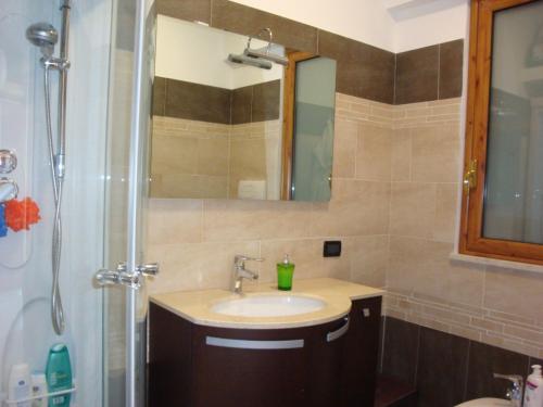 a bathroom with a sink and a shower with a mirror at La Suite in SantʼAlessio Siculo