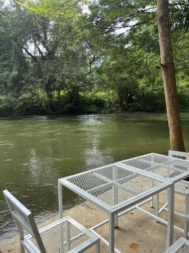 a table and two chairs next to a river at Baan LungYod Resort in Phetchaburi
