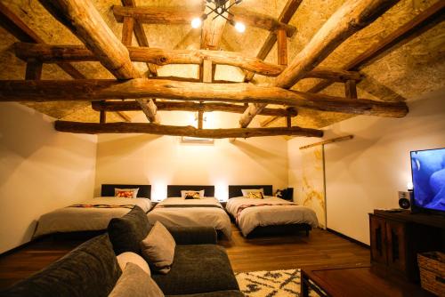 a bedroom with two beds and a couch in a room at 蔵の宿ねこざえもん別館はるみ in Katori