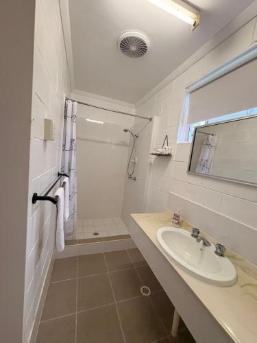 a white bathroom with a sink and a shower at Mitchell Motel & Cabins in Mitchell