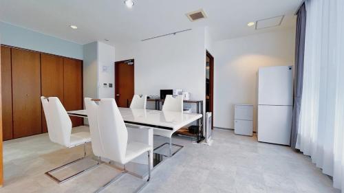a dining room with a white table and white chairs at Fierement inn in Sapporo