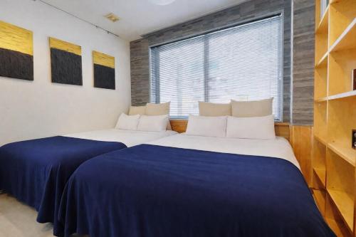 two beds in a room with a window at Fierement inn in Sapporo