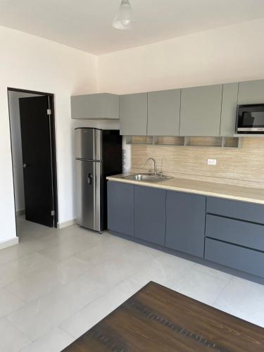 a kitchen with blue cabinets and a stainless steel refrigerator at Loftstay MYO in Monterrey