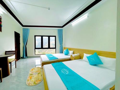 a room with two beds and a desk in it at Nhà Nghỉ Mũi Giày in Mù Cang Chải