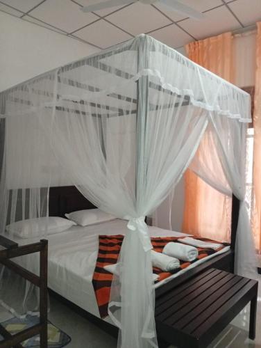 a bedroom with a canopy bed with a wooden bench at Villa Aloe Vera- Signature Rooms in Weligama