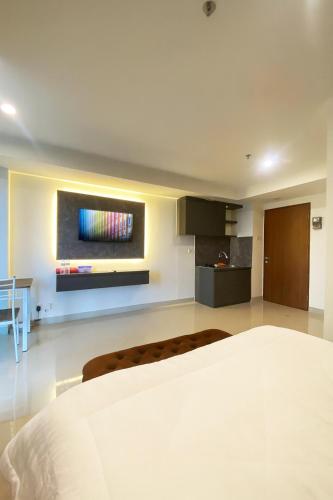 a bedroom with a bed and a tv on the wall at Grand Kamala Lagoon by Whitebox in Bekasi