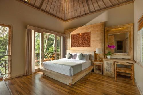 a bedroom with a bed and a desk and windows at Royal Arkara Villas by Arkamara in Ubud