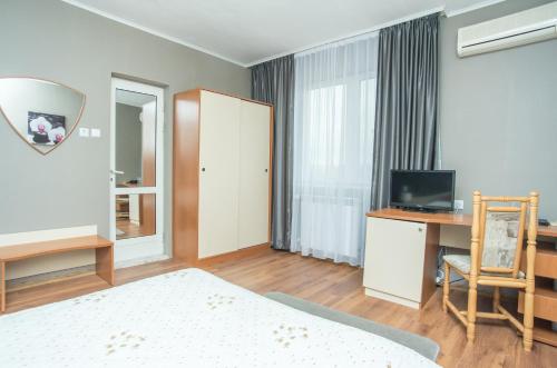 a bedroom with a bed and a desk and a television at Family Hotel Accent in Razgrad