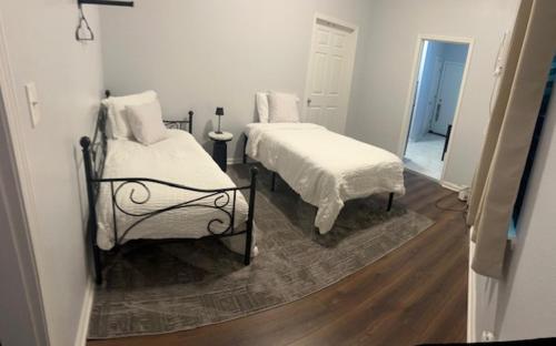 a bedroom with two beds with white sheets and a rug at Trisuites 2 in New Orleans