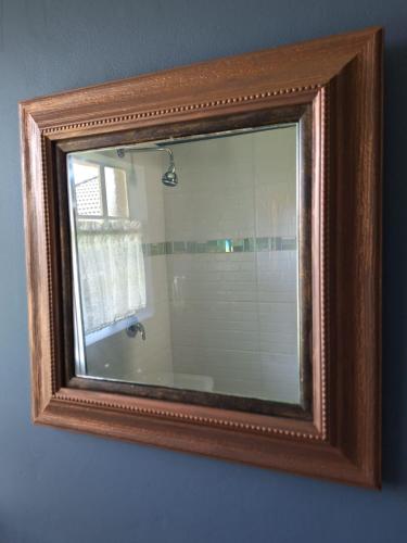 a mirror in a wooden frame hanging on a wall at The Pebble in Howick
