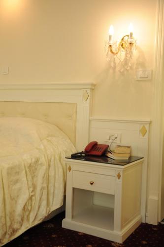 a bed with a night stand with a phone on it at Millenium Palace in Ohrid