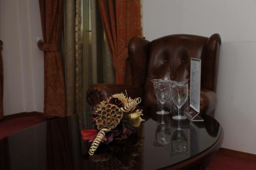 a glass table with wine glasses and a leather chair at Millenium Palace in Ohrid
