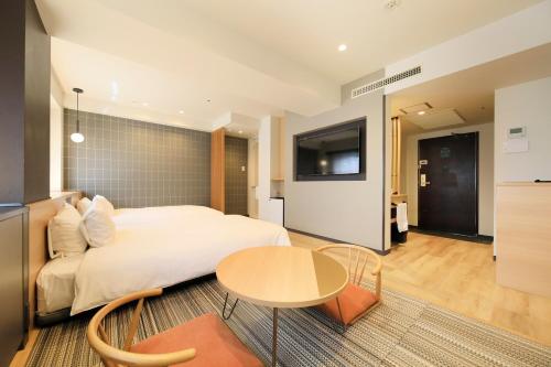a bedroom with a bed and a table and a tv at Richmond Hotel Matsumoto in Matsumoto