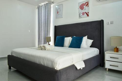 a bedroom with a large bed with blue pillows at Aqua Azuri apartment in Mombasa