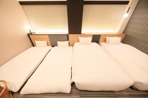 two twin beds in a room with two windows at Richmond Hotel Matsumoto in Matsumoto