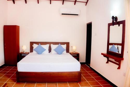 a bedroom with a white bed and a mirror at Samaya Waters Bentota in Haburugala