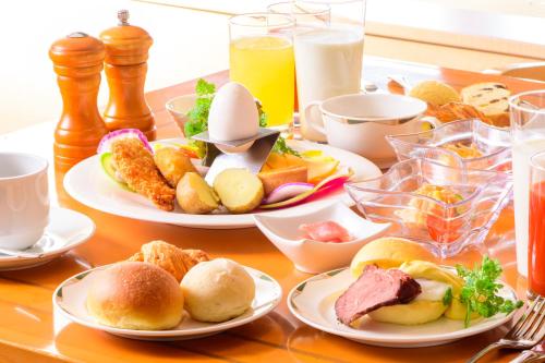 ein Tisch mit Tellern mit Frühstücksspeisen in der Unterkunft Authent Hotel Otaru in Otaru
