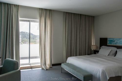 a hotel room with a bed and a large window at Hotel Praia in Nazaré