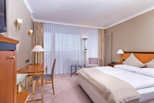 a hotel room with a bed and a desk at Wyndham Garden Lahnstein Koblenz in Koblenz