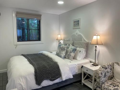 a white bedroom with a bed and a chair at Salty Kisses in Narrabeen