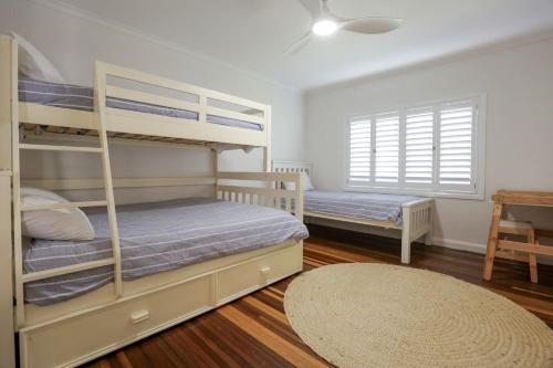 a bedroom with two bunk beds and a table at Bungalow Blue - 8 Illawong Lane in Evans Head