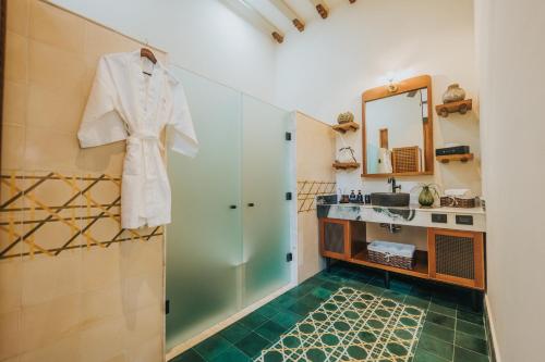 ein Badezimmer mit Dusche und einem an der Wand hängenden Bademantel in der Unterkunft CIGNO Mejorada Hotel Boutique in Mérida