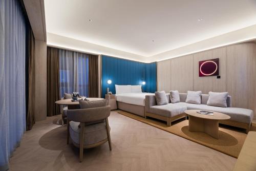 a hotel room with a bed and a couch at Orange Crystal Hotel Yantai Binhai Square in Yantai